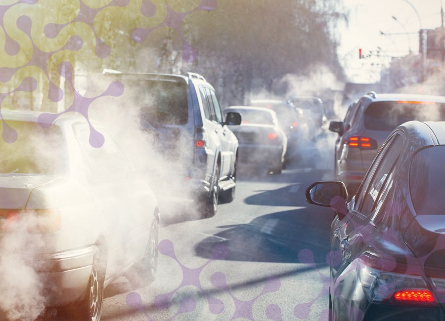 a stock photograph showing a congested street with cars emitting smokes into the sky.