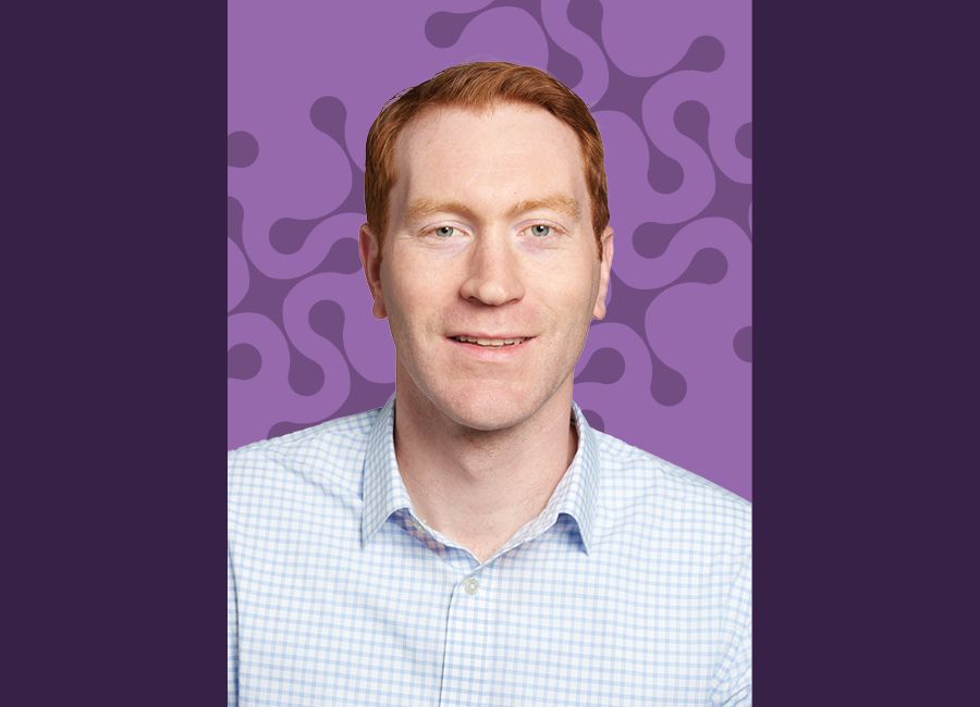 a portrait of a red hair man smiling at the camera with an abstract molecule background.