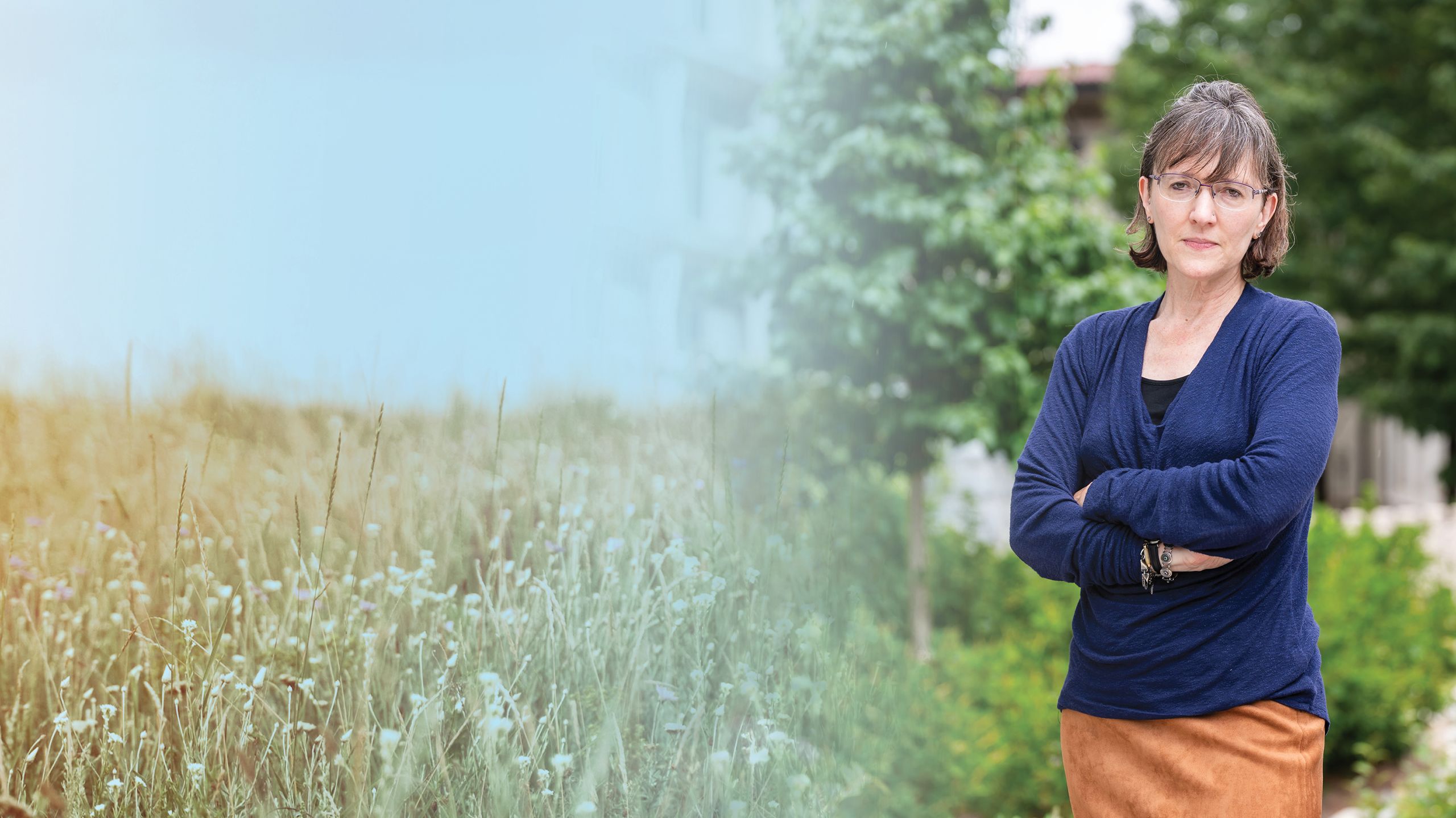 a photo illustration background of a wildflower field on the left and hannah copper on the right in front of a building with trees with her arms crossed.