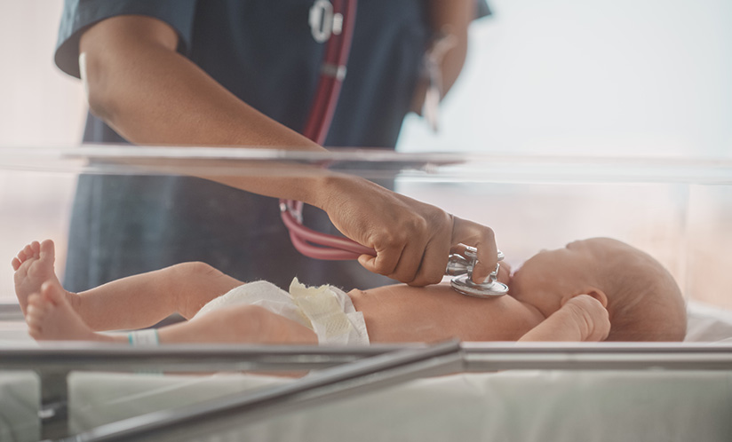 Health care worker checking on infant with stethoscope