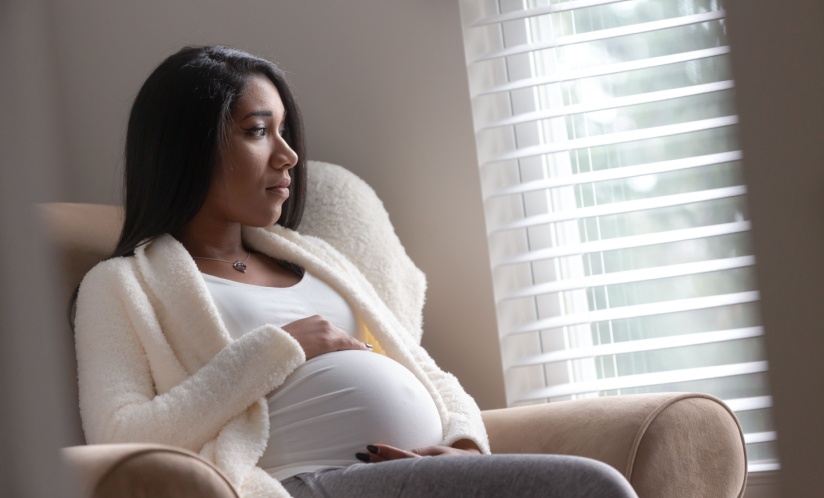 Pregnant Black woman looking out a window