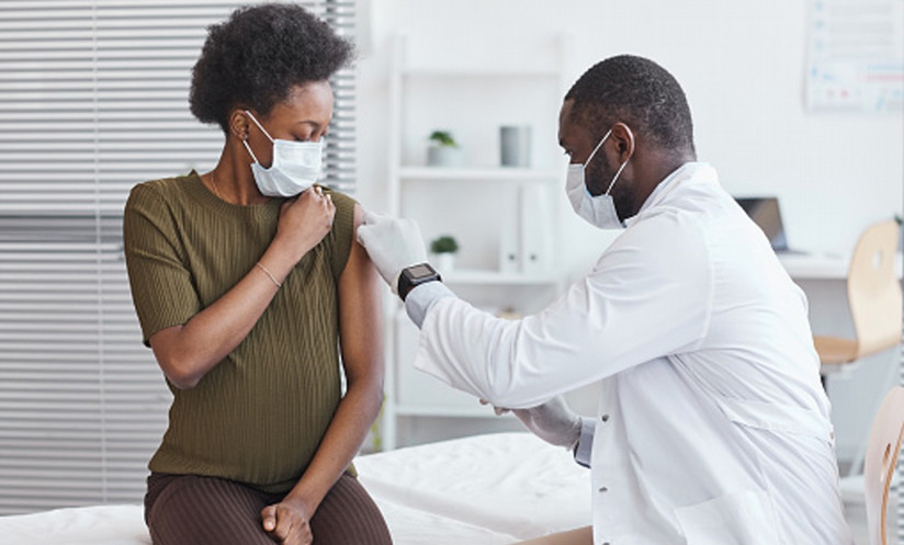 pregnant woman receiving a vaccine and wearing a mask