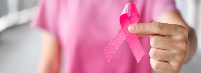 A woman holding up a breast cancer ribbon