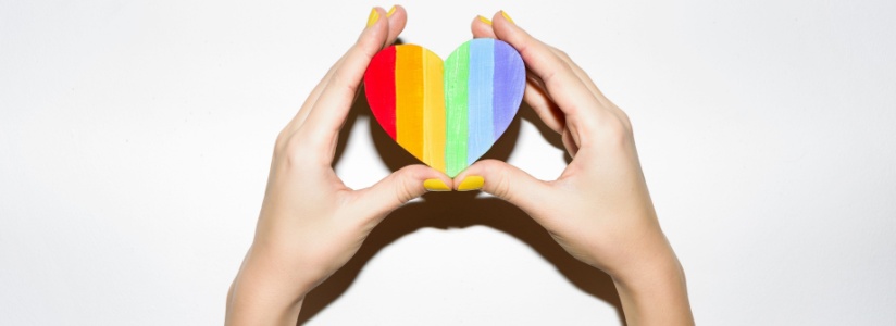 Hands holding up a rainbow heart