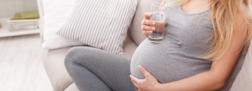 A pregnant woman holding a glass of water