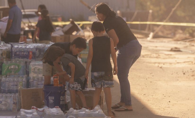 Image of a family with bottled water in the aftermath of Hurricane Helene