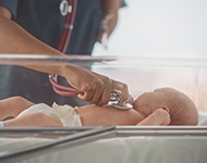 Health care worker checking on infant with stethoscope