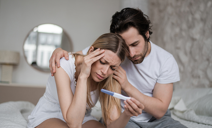 Woman and man looking at pregnancy test concerned