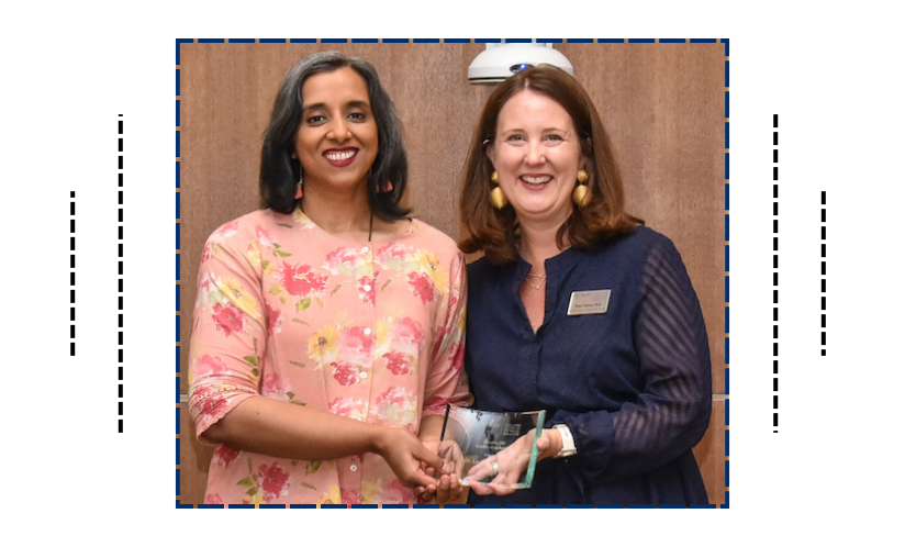 Two women holding an award