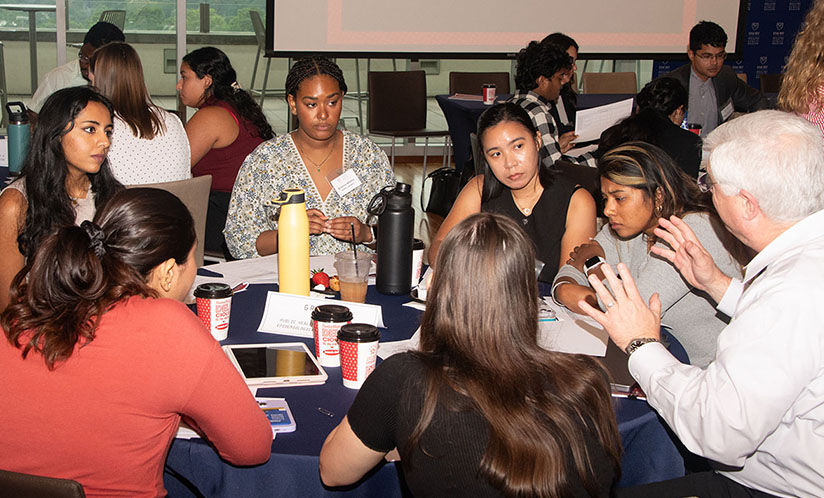 Students sitting at table listening to professor