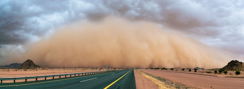 A cloud of dust over a road in the desert.