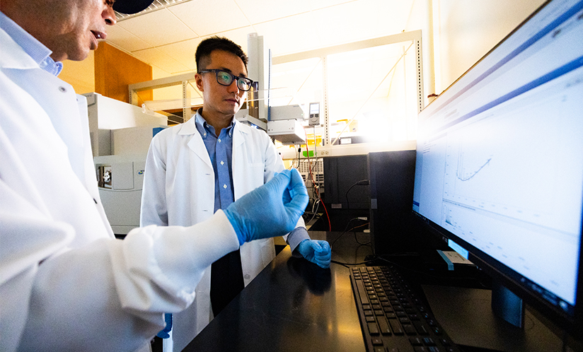 Two male researchers looking at computer