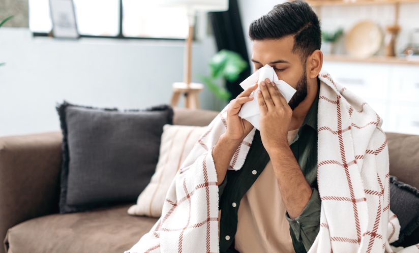 man on a couch blowing nose