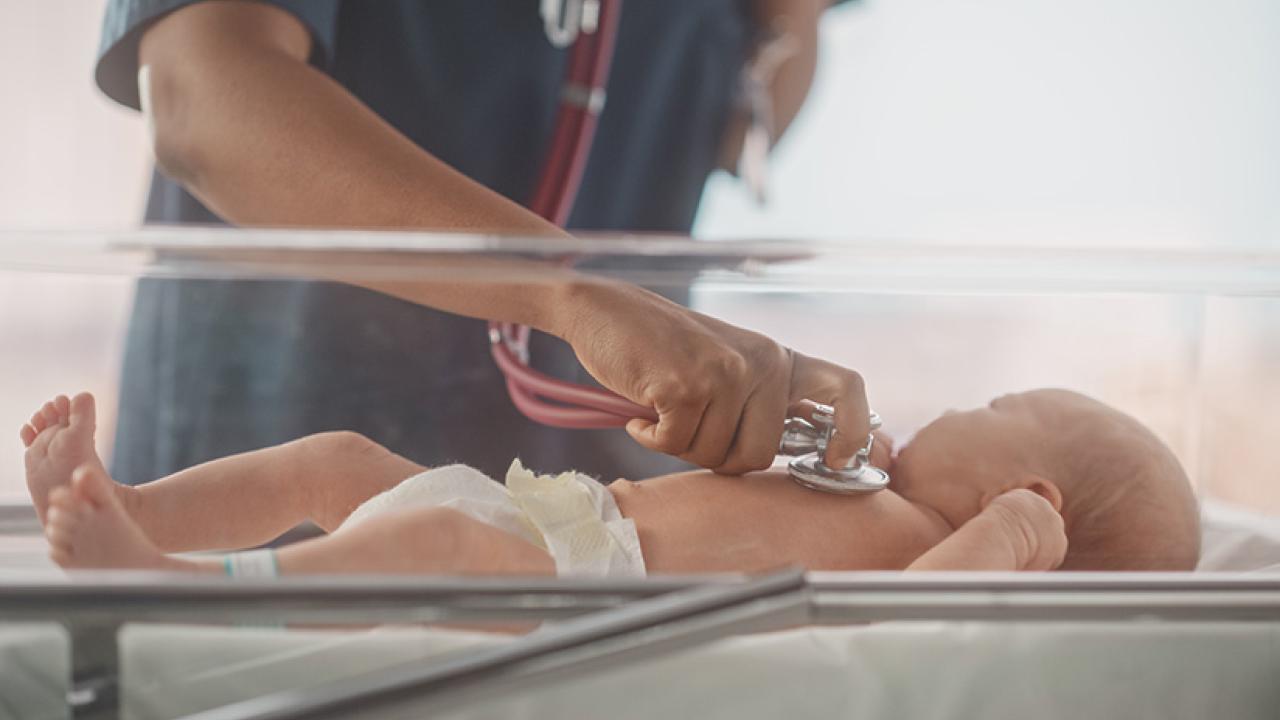 Health care worker checking on infant with stethoscope