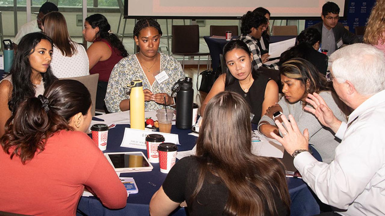Students sitting at table listening to professor