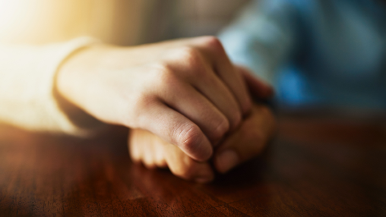 Two people holding hands in comfort.