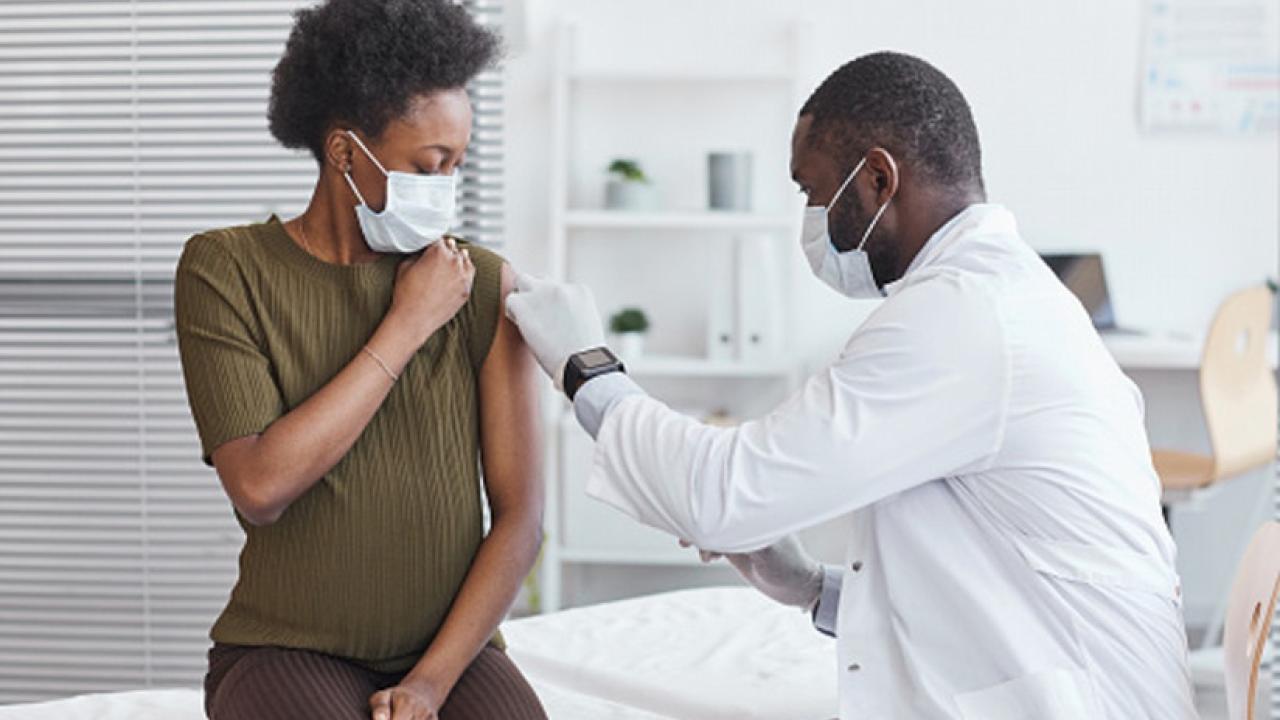 pregnant woman receiving a vaccine and wearing a mask